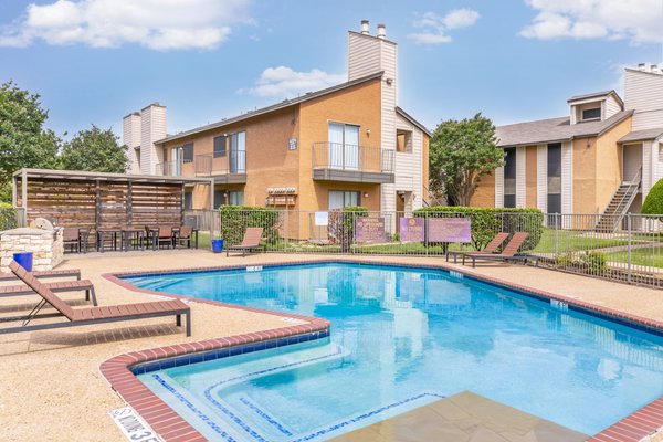Swimming pool with lounge chairs and a shaded pergola at Amber Creek Apartments