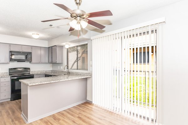 Renovated kitchen with granite countertops, gray cabinets and a ceiling fan